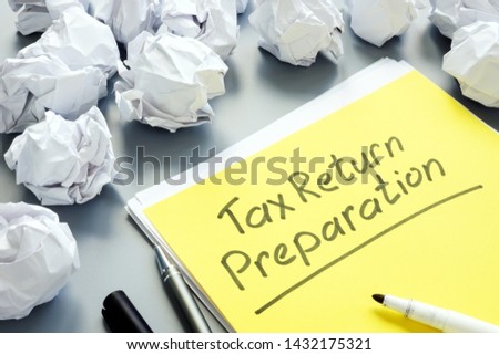 Tax Return Preparation concept and stack of papers.