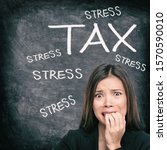 Tax season stress stressed Asian woman biting nails anxious late to file tax paperwork for IRS. Black chalkboard background with text written for income tax returns.