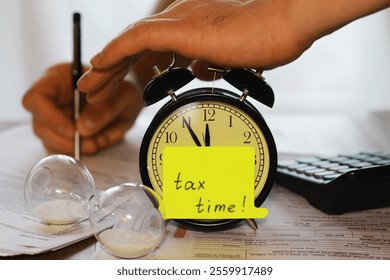 Tax Time Concept: Deadline Reminder with Alarm Clock, Papers, and Sand Timer Setup - Powered by Shutterstock