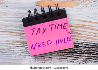 Tax time message on a paper of mini notepad. Need any help with your taxes. White wood on the background.