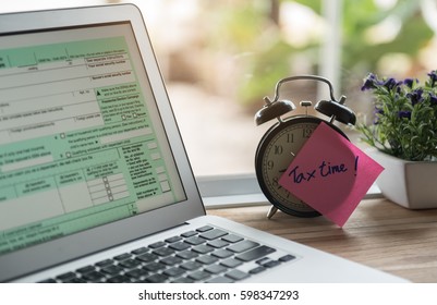 tax time post-it on alarm clock and Individual income tax return form online.