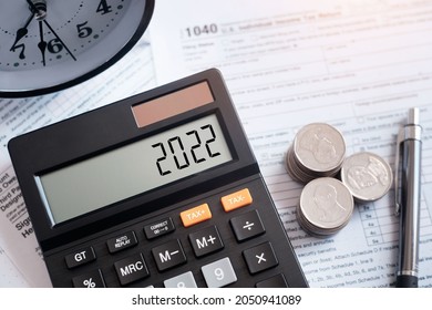 Tax word and 2022 number on calculator. pen and coin on 1040 tax form. Business tax. The new year 2022 tax concept.