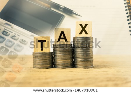 Taxation and Annual tax concept. A wooden block with message on stacked coins on wood table exposure with calculator, notebook and black pen. Depicts a income planning, annual tax deduction.
