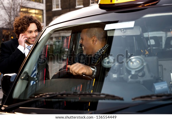 Taxi cab\
driver communicating with male\
passenger.