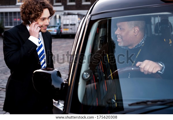Taxi cab\
driver communicating with male\
passenger