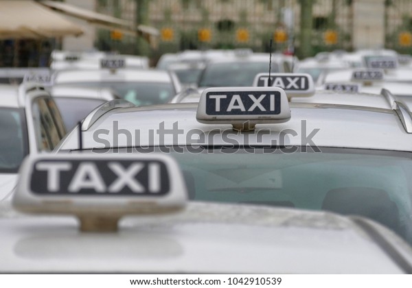 Taxi cab parked in rows waiting customers close up\
of sign on roof of cars