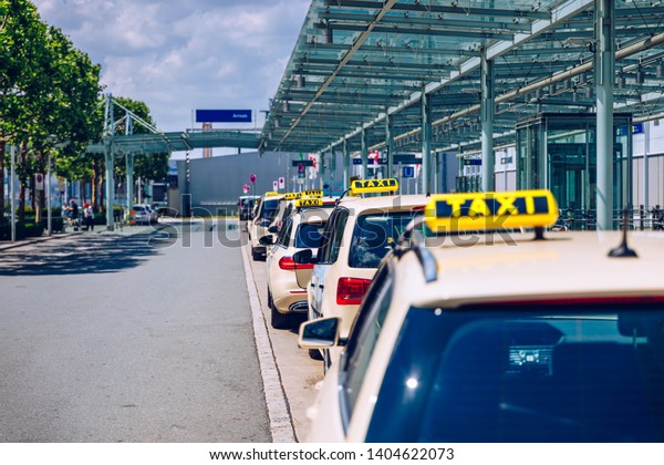 Taxi\
cabs waiting for passengers. Yellow taxi sign on cab cars. Taxi\
cars waiting arrival passengers in front of Airport Gate. Taxis\
stand on Airport Terminal waiting for\
passengers.