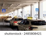 Taxi car Queue yellow taxi symbol  on roof stand waiting at parking of airport terminal or railway station Under Concrete Structure Transportation Hub. Urban street transportation comfort service