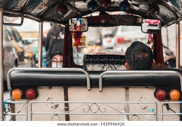 Taxi car (Tuk Tuk) and driver relax at\
Yaowarat road or Chinatown of Bangkok,\
Thailand