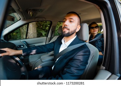 Taxi driver driving a car with elegant female passenger.