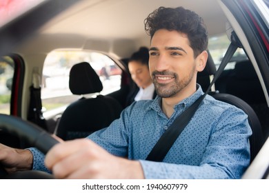 Taxi Driver With Passenger At Back Seat.