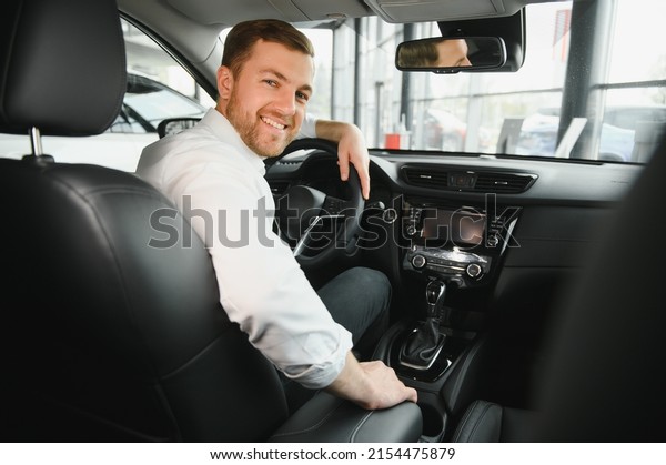 Taxi driver\
smiling while turning over to the backseat looking talking with\
clients. Successful businessman husband looking at the backseat at\
dealer shop before buying a\
car.