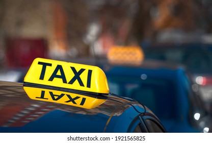 Taxi Light Sign Or Cab Sign In Yellow Color On Top Of The Car, Blurred Background. Taxi Car Sign On Cab Roof While Parking On Road Waiting For Passaenger. Taking Safe Rideshare During Covid