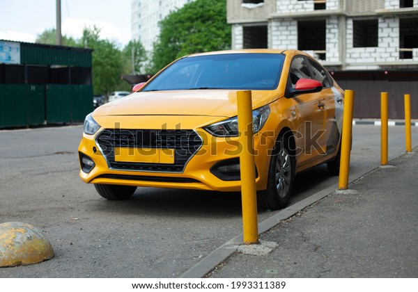 Taxi in the parking lot. A yellow car is parked\
outside the house. The taxi is thrown near the yellow posts.\
Waiting for the car.