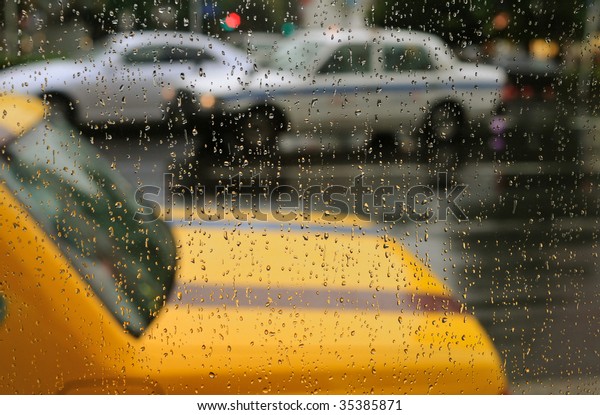 taxi parking lot taken through rainy drops on\
window; focus on water\
drops