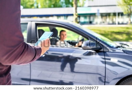 Taxi phone app for cab or car ride share service. Customer waiting driver to pick up on city street. Man holding smartphone. Mobile and online booking for rideshare transportation with cellphone.