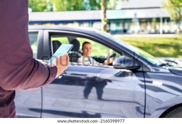 Taxi phone app for cab or car ride share\
service. Customer waiting driver to pick up on city street. Man\
holding smartphone. Mobile and online booking for rideshare\
transportation with\
cellphone.