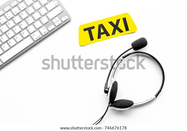 Taxi service online. Taxi\
label, keyboard, headphones on white background top view\
copyspace