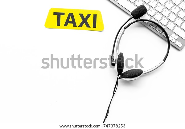 Taxi service online. Taxi\
label, keyboard, headphones on white background top view\
copyspace