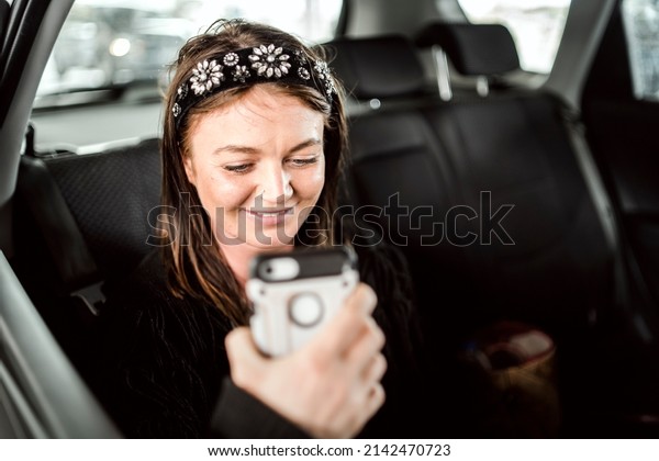 A taxi or Uber passenger talking through the phone on\
the back seat 
