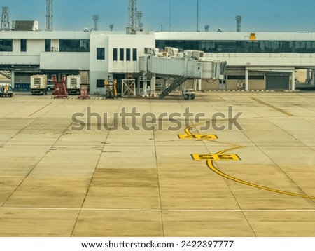 Taxiway marking yellow lines that guides pilots during maneuvering to the parking bay in a blur background of the airport terminal 