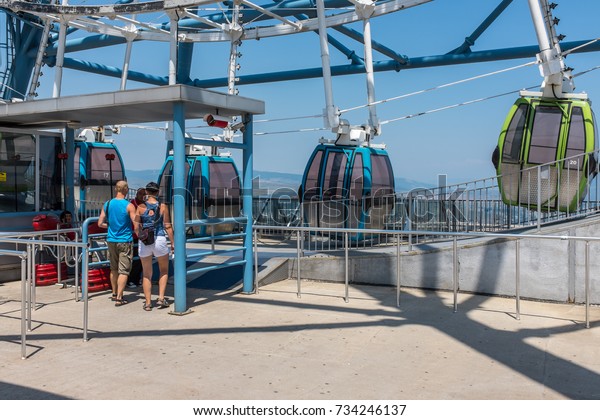 TBILISI, GEORGIA, EASTERN EUROPE - JULY 15TH,\
2015 : Passengers waiting to board the Big Ferris Wheel at\
Mtatsminda Park, overlooking the city of\
Tbilisi.