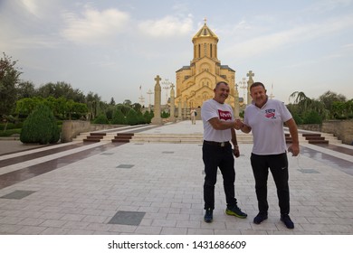 Tbilisi, Georgia - June 23, 2019: Two Happy Men Shaking Hands, Standing Near Cathedral Church. Meeting Of Old Friends. 