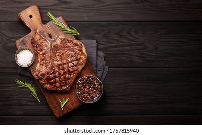 T-bone grilled beef steak with spices and herbs. Top view flat lay with copy space