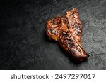 T-bone steak. Prime Black Angus beef steak on a black slate background. Top view.