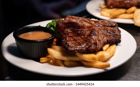 T-bone Steak Served With Chips, Vegetables And Gravy.