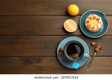 Tea Bag In Ceramic Cup Of Hot Water, Dessert And Sugar Cubes On Wooden Table, Flat Lay. Space For Text