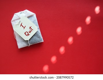 Tea Bag On Red Background With Handwritten Text On Tag I QUIT, Concept Of Decision Making To Quit Job , Leave Workplace, Resign From Full Time Corporate Job Or Quit Bad Habits