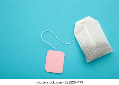 Tea bag with pink blank label on blue background. Copy space for text. Top view - Powered by Shutterstock