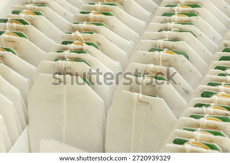 Tea bags in parallel rows with green and yellow tags.