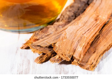 Tea and bark of cat's claw plant on wooden background, uncaria tomentosa