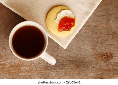 Tea with a butter cookie smothered with cream cheese and jam. With space for text.