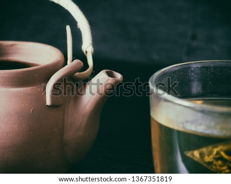 Tea. Clay teapot with grean tea in glass mug on dark background. Tea set with black background.