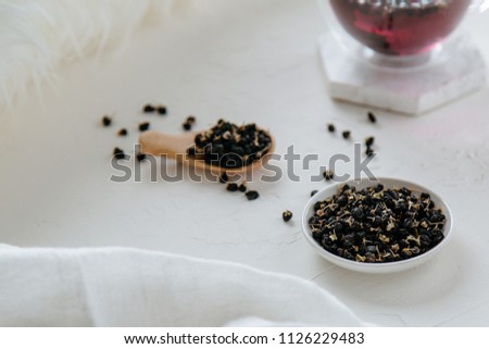 Tea in clear glass cup made with black wolfberries against clean white background.