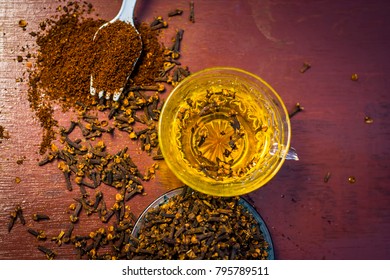 Tea Of Clove,Syzygium Aromaticum With Powder Of Clove And Raw Clove On A Wooden Surface.