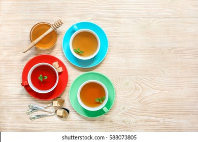 Tea Collection Of Three Different Types Of Tea - Mint, Hibiscus And Herbal Tea In Cups Isolated On Light Wooden Background. Horizontal. View From Above.