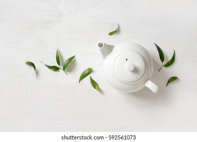 Tea Concept, Teapot With Tea Surrounded With Green Tea Leaves, View From Above