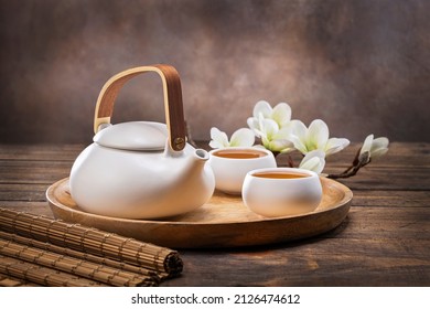 Tea concept with white tea set of cups and teapot with fresh tea on wooden background with copy space. 