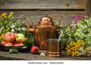 Tea in a copper mug with a teapot on a wooden table, rustic retro style