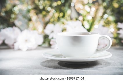 Tea cup in front of blurred nature background of flowers and leaves. Bokeh concept - selective focus - Shutterstock ID 1898717404