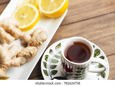 Tea cup with lemon and ginger on white plate. Infusion.
