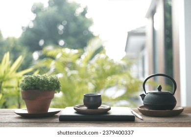 Tea cup and metal teapot and plant pot on wooden table outdoor relaxing drinking - Powered by Shutterstock