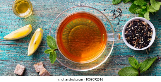 Tea cup with mint leaf and lemon. Wooden background. Copy space. Top view.