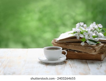 tea cup, old books and apple flowers on wooden table in garden. tea party. spring season. atmosphere gentle romantic image. copy space - Powered by Shutterstock