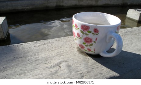 Tea Cup On Cement Floor Next To A Public Pool In The City