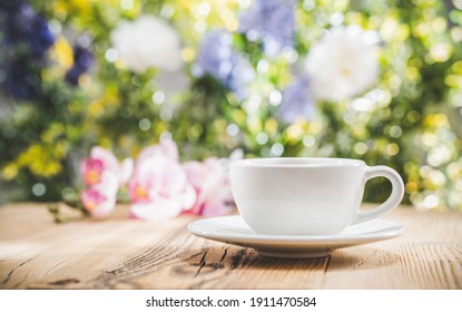 Tea Cup On Wooden Table In Front Of Floral Spring Garden Nature Outdoor With Bokeh Light. Front View